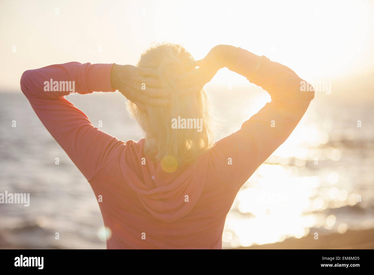 Ältere Frau erstreckt sich vom Strand Stockfoto