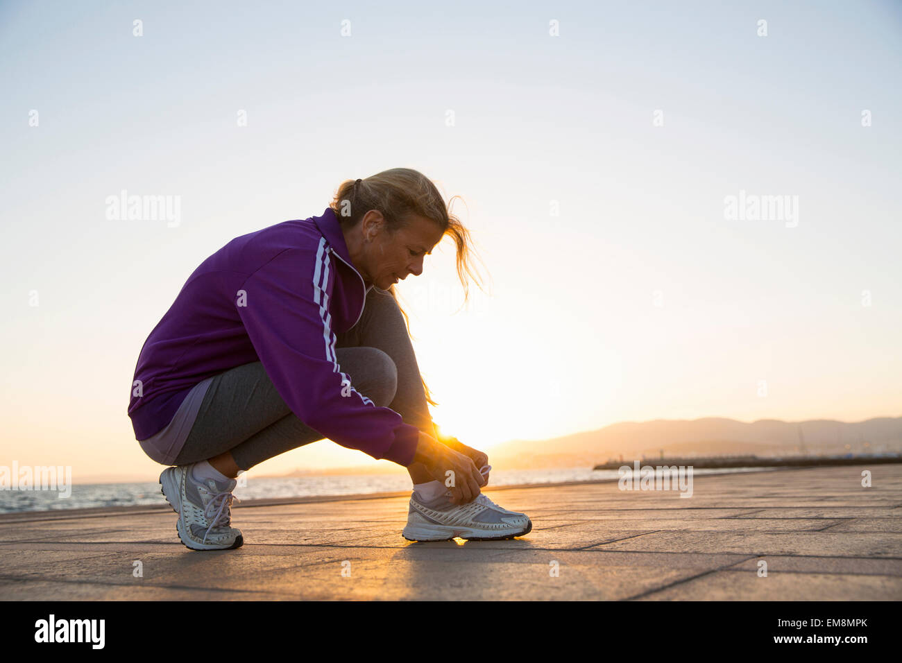 Reife Frau binden Schnürsenkel Strand Stockfoto