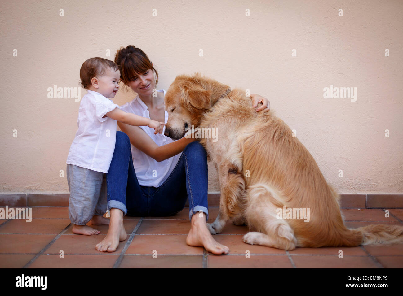 Mitte Erwachsene Frau mit Baby Tochter Petting Hund in Küche Stockfoto