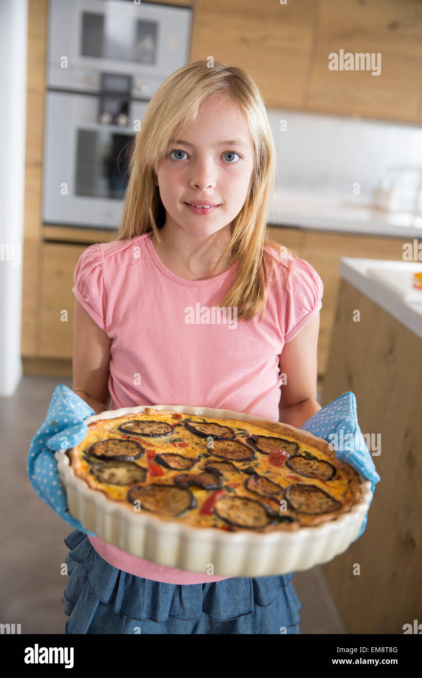 Porträt eines Mädchens mit hausgemachten Aubergine, Spinat und Zwiebel Quiche in Küche Stockfoto