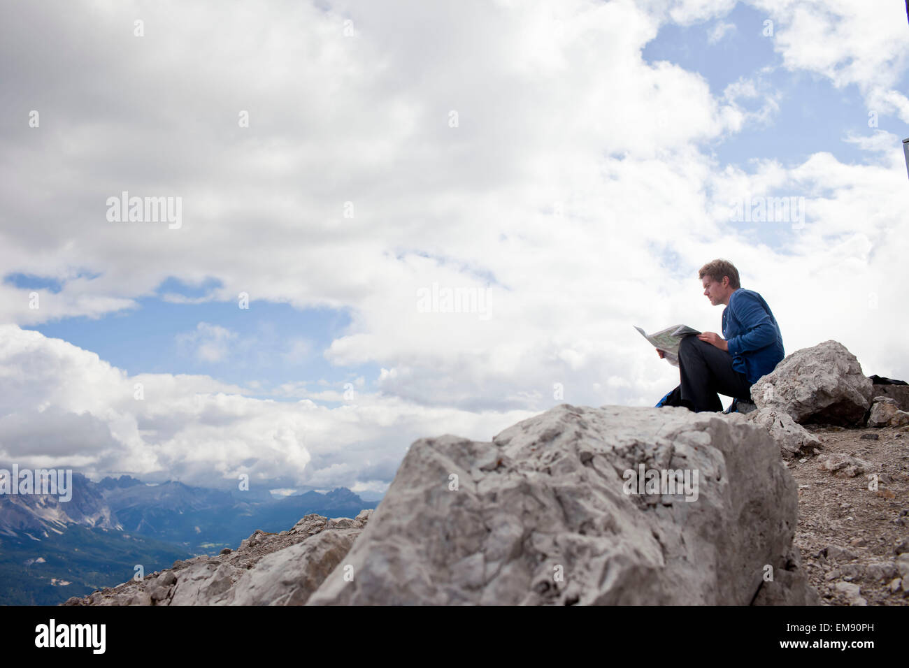 Männliche Wanderer sitting on Top of Mountain Rock Lesung Karte, Peitlerkofel, Südtirol, Italien Stockfoto