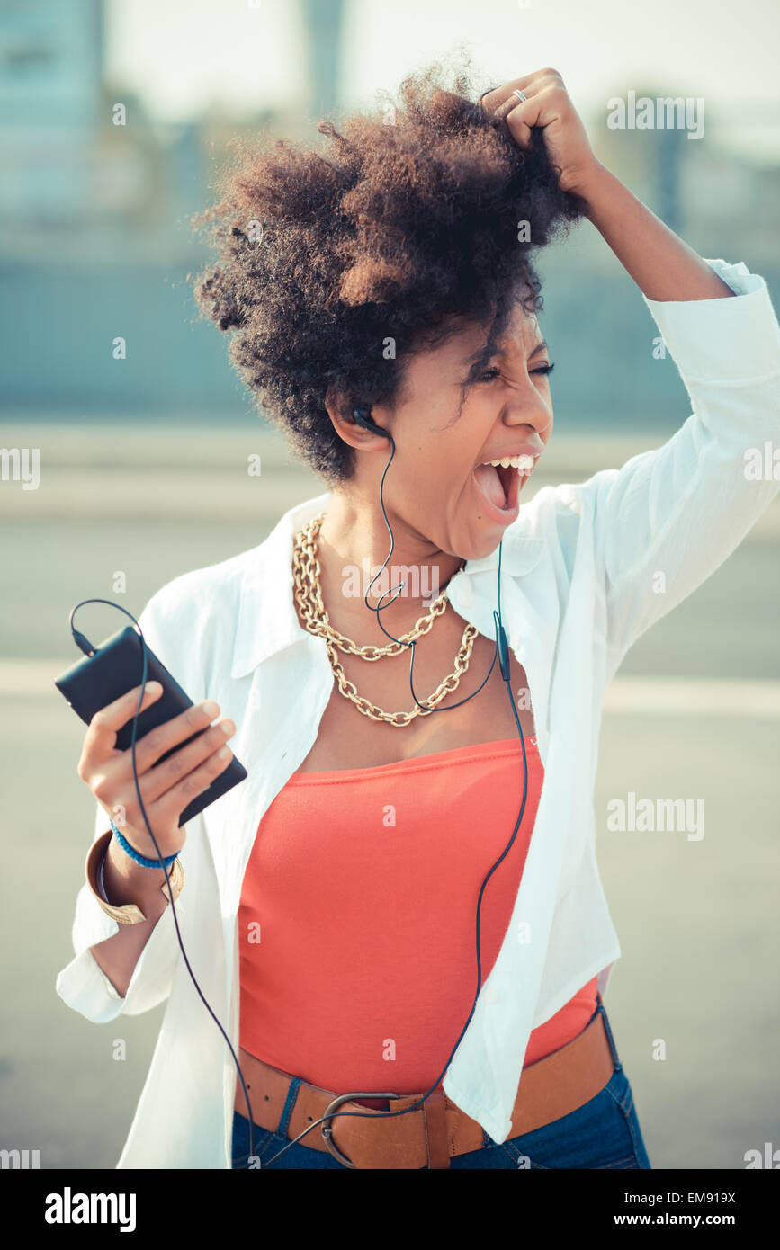 Junge Frau mit Musik über Kopfhörer in Stadt singen Stockfoto