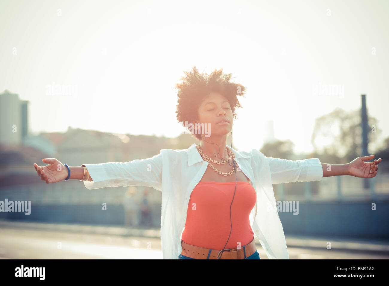 Junge Frau mit offenen Armen in Stadt Smartphone Musik tanzen Stockfoto