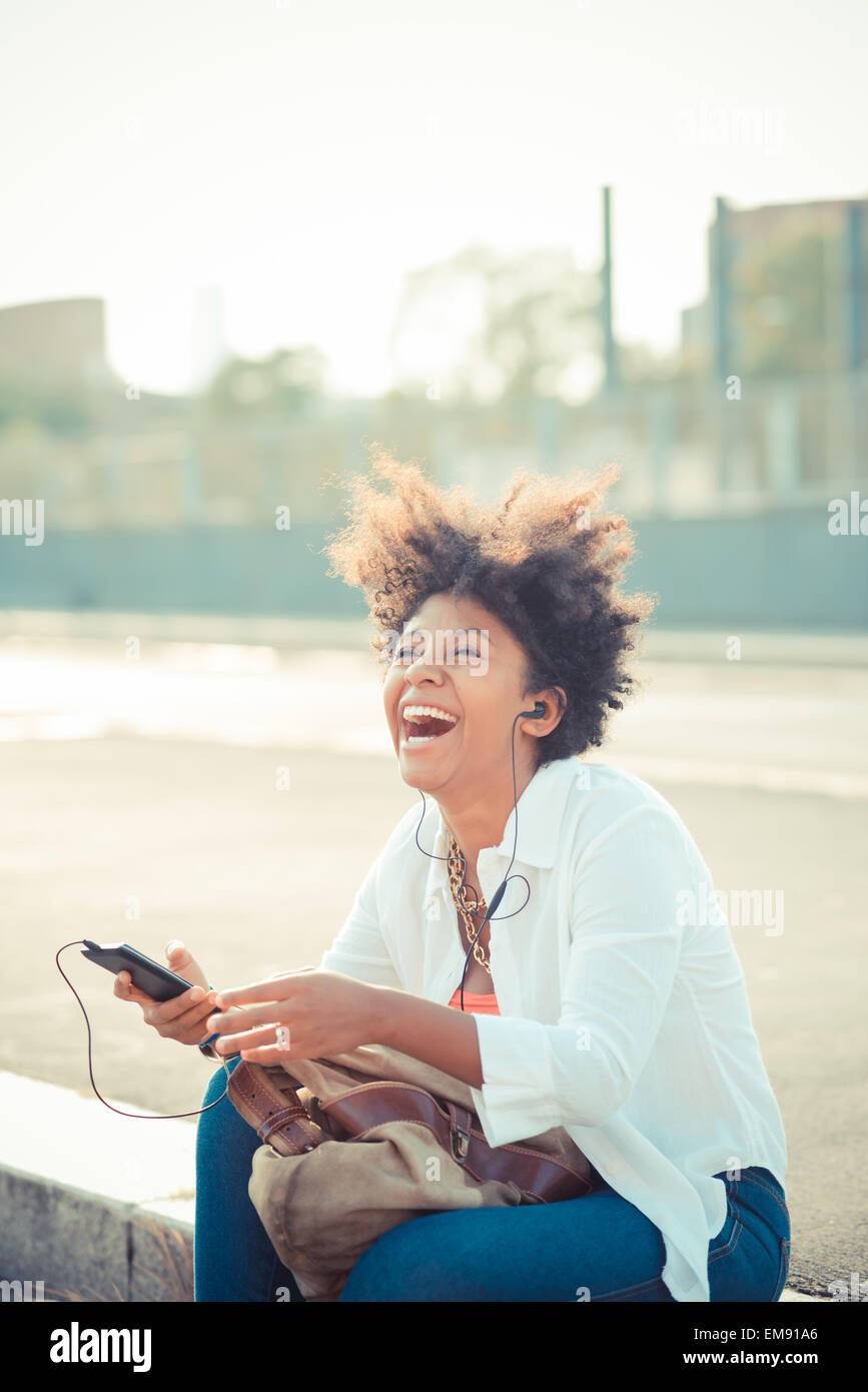 Junge Frau lachend und Smartphone Musikhören im Stadt-Parkplatz Stockfoto