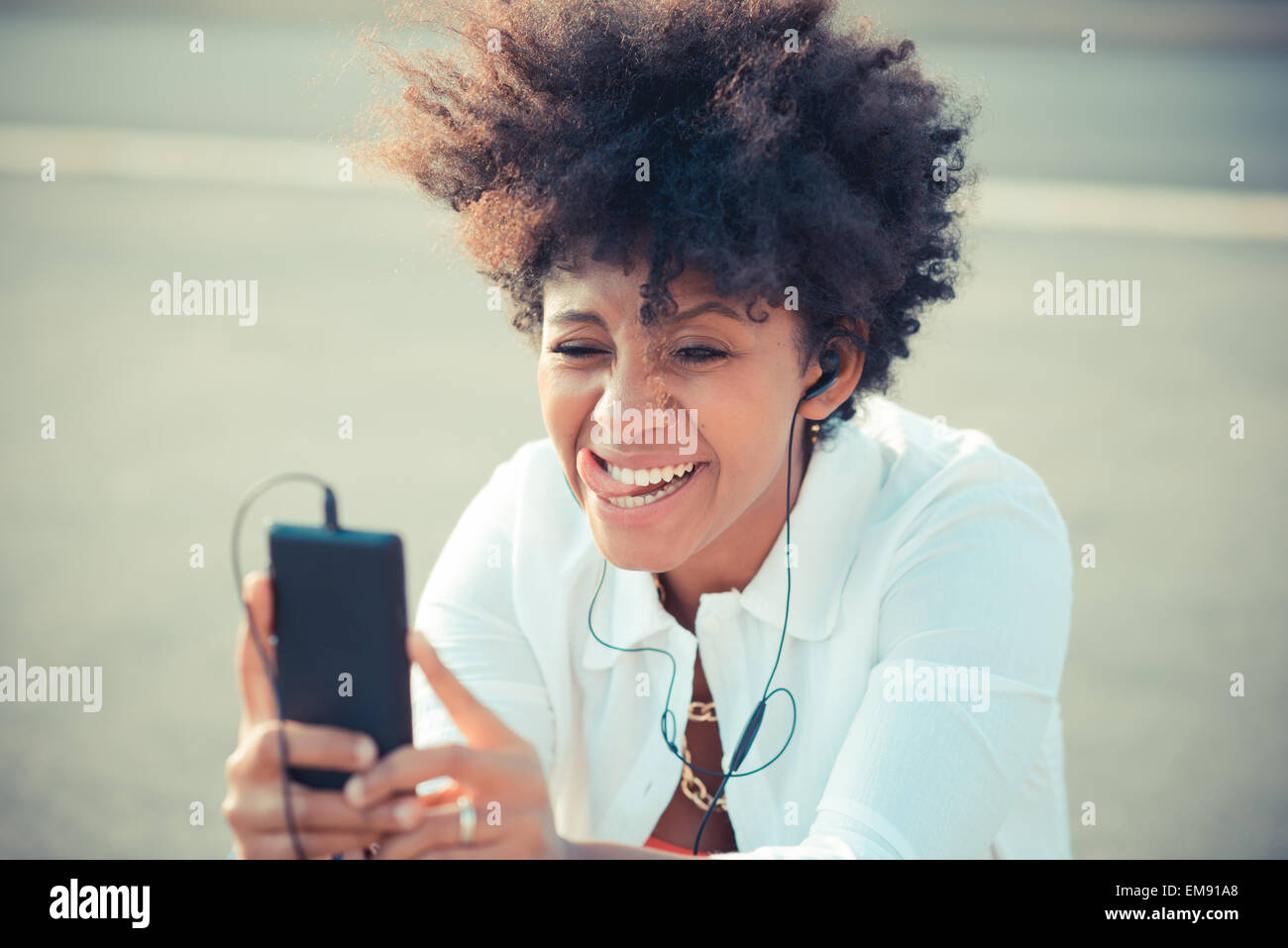 Junge Frau Auswahl Smartphone Musik in Stadt Parkplatz Stockfoto