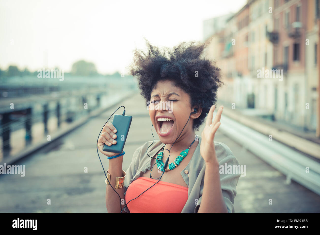 Junge Frau schreiend auf Musik von Smartphone im Industriegebiet der Stadt Stockfoto