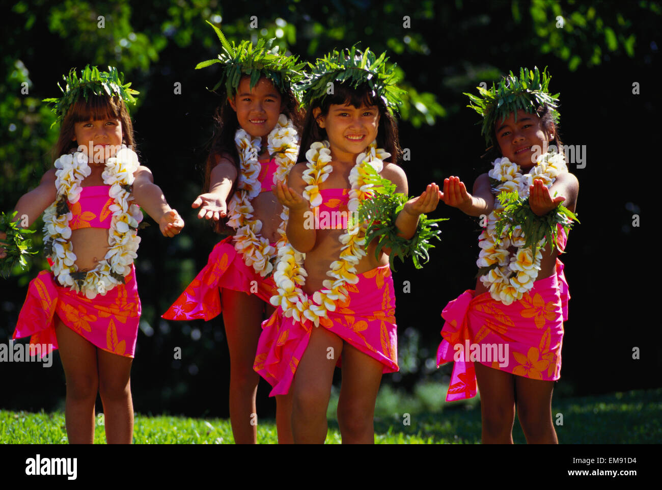 Junge Keiki Hula Halau tanzen In bunten Pareos mit Haku und Leis Stockfoto