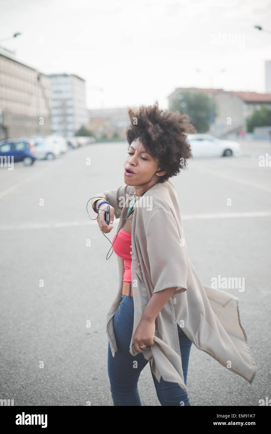 Junge Frau gehen und tanzen Kopfhörer Musik in Stadt Parkplatz Stockfoto