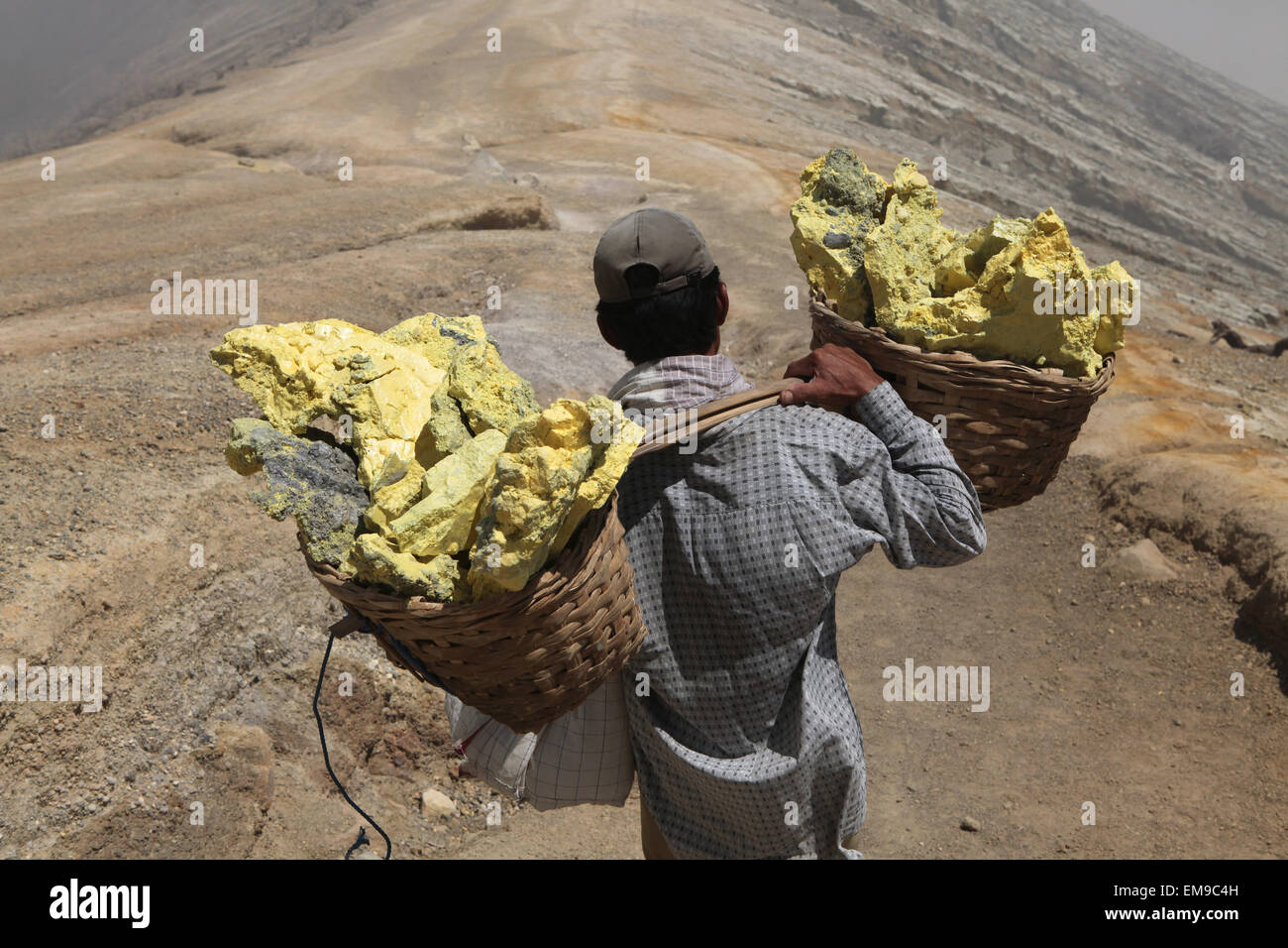 Schwefel Minen Kawah Ijen, Ost-Java, Indonesien. Bergmann trägt Körbe mit Schwefel im Rauch der giftige vulkanische Gase. Stockfoto