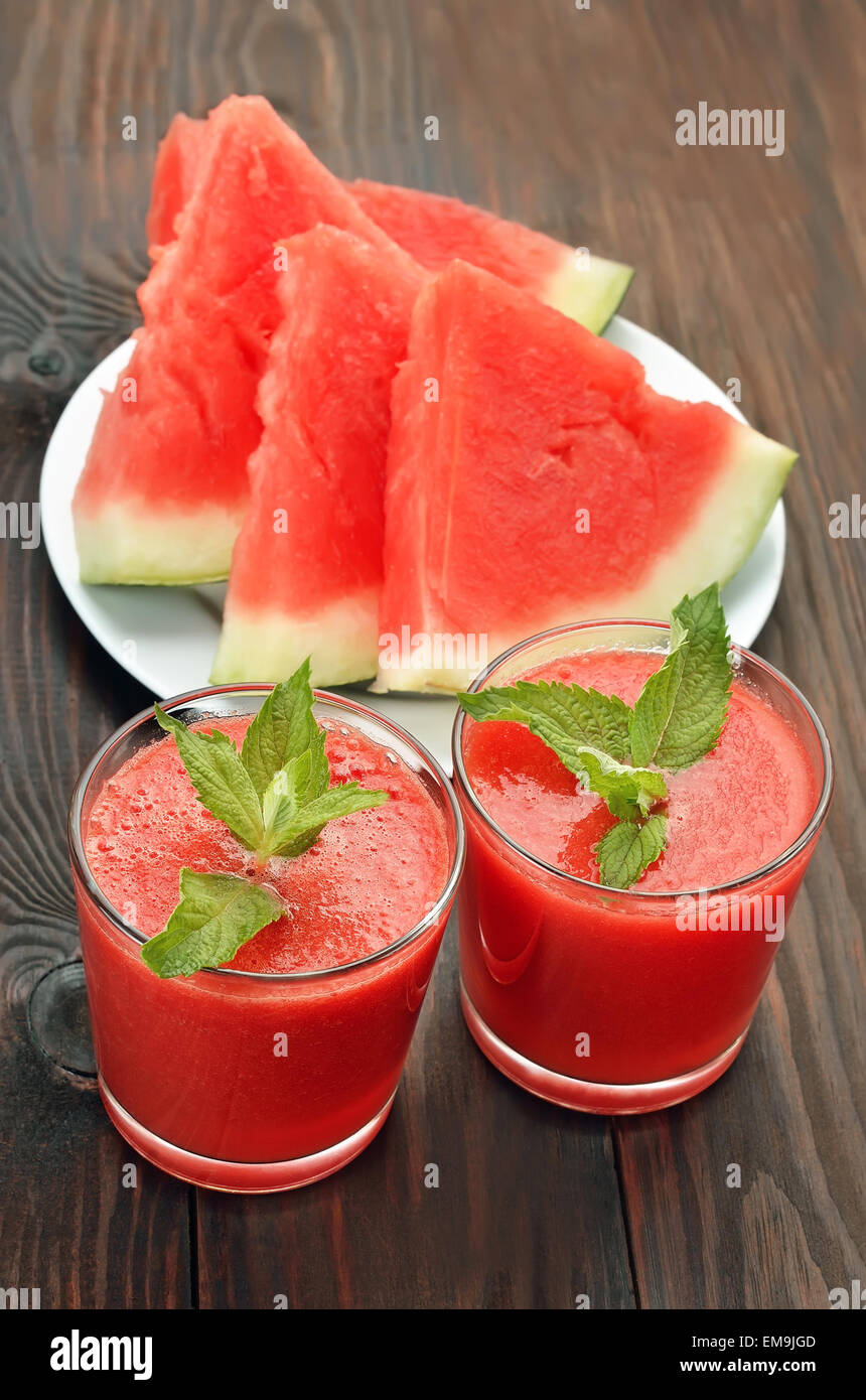 Wassermelone-cocktail im Glas und Scheiben auf Holztisch Stockfoto