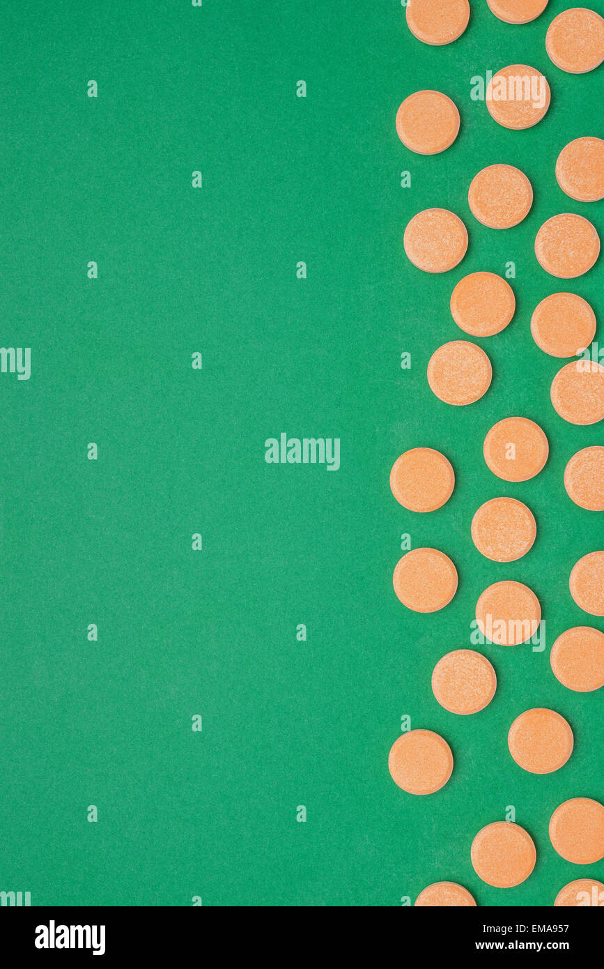 Orange Vitamin-Pillen auf grünem Hintergrund Stockfoto