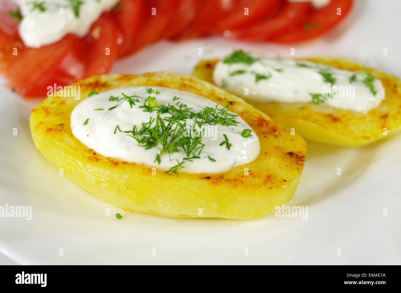 Ofenkartoffel mit Quark, Schnittlauch und Tomaten auf einem weißen Teller Stockfoto