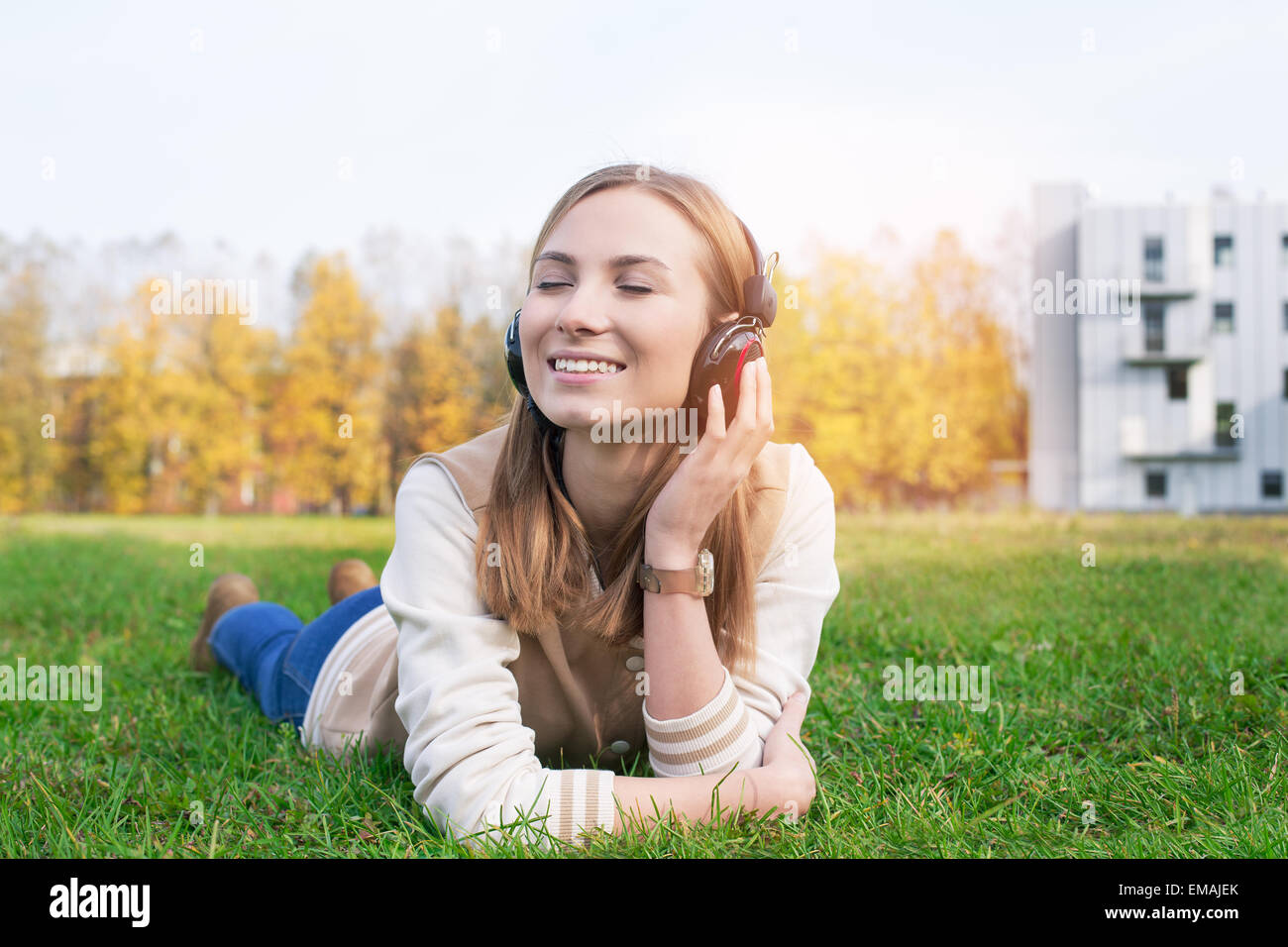 Schüler auf dem grünen Rasen liegen und hören Musik in Kopfhörer mit geschlossenen Augen Stockfoto
