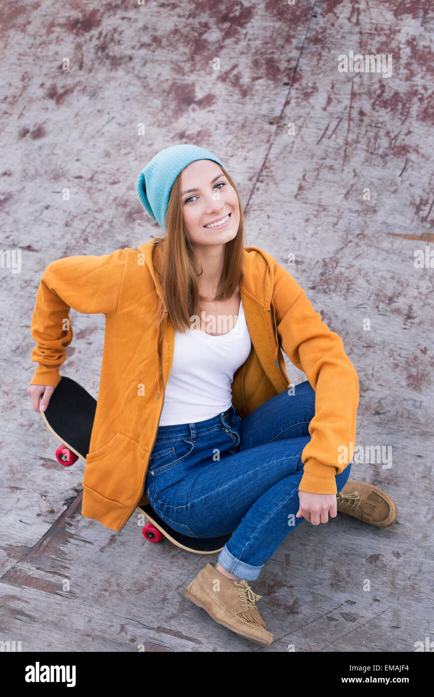 Schüler sitzen auf einem Skateboard und lächelt in die Kamera Stockfoto