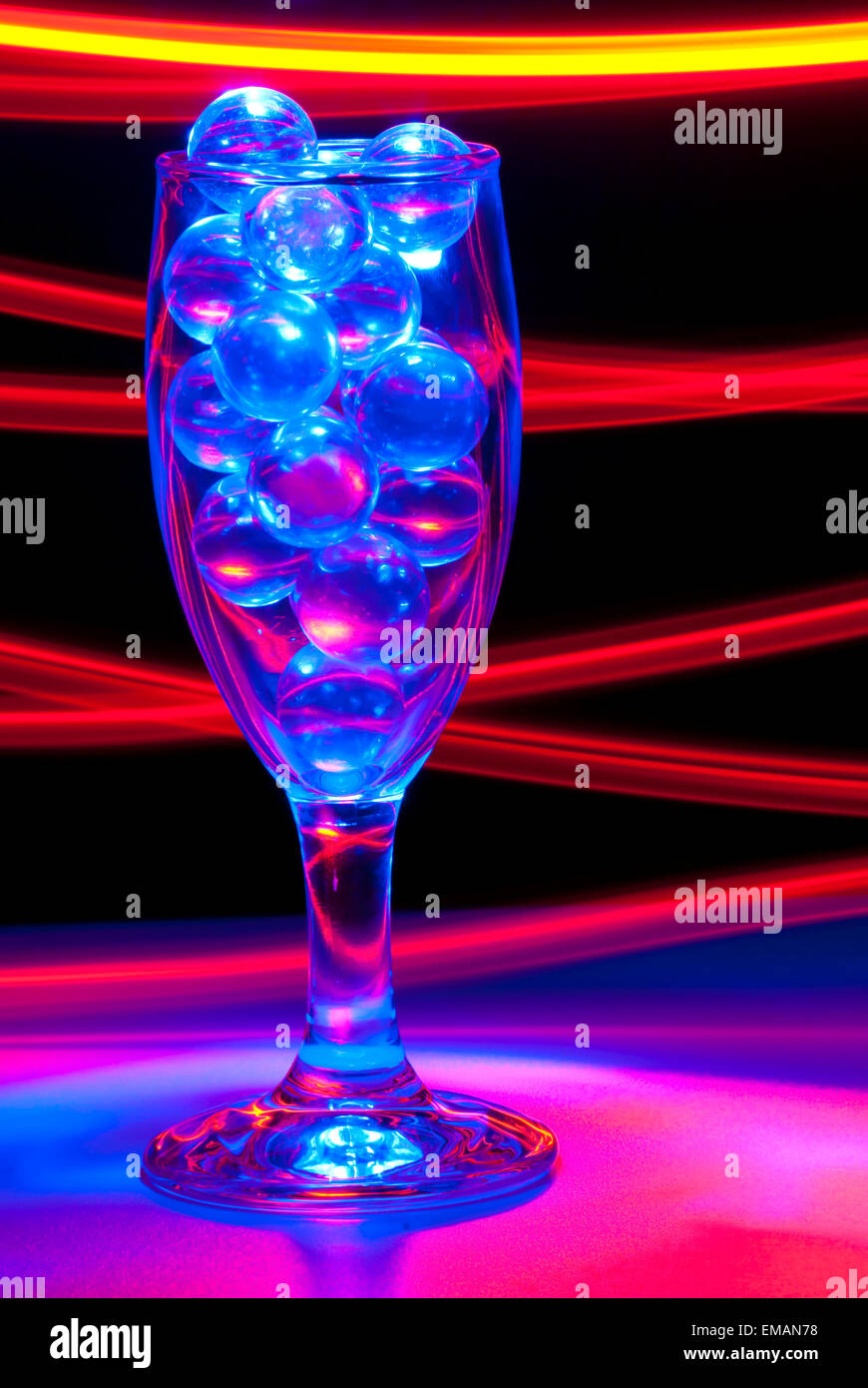 Klar, Murmeln in ein Weinglas mit blauem und rotem Licht Malerei Stockfoto