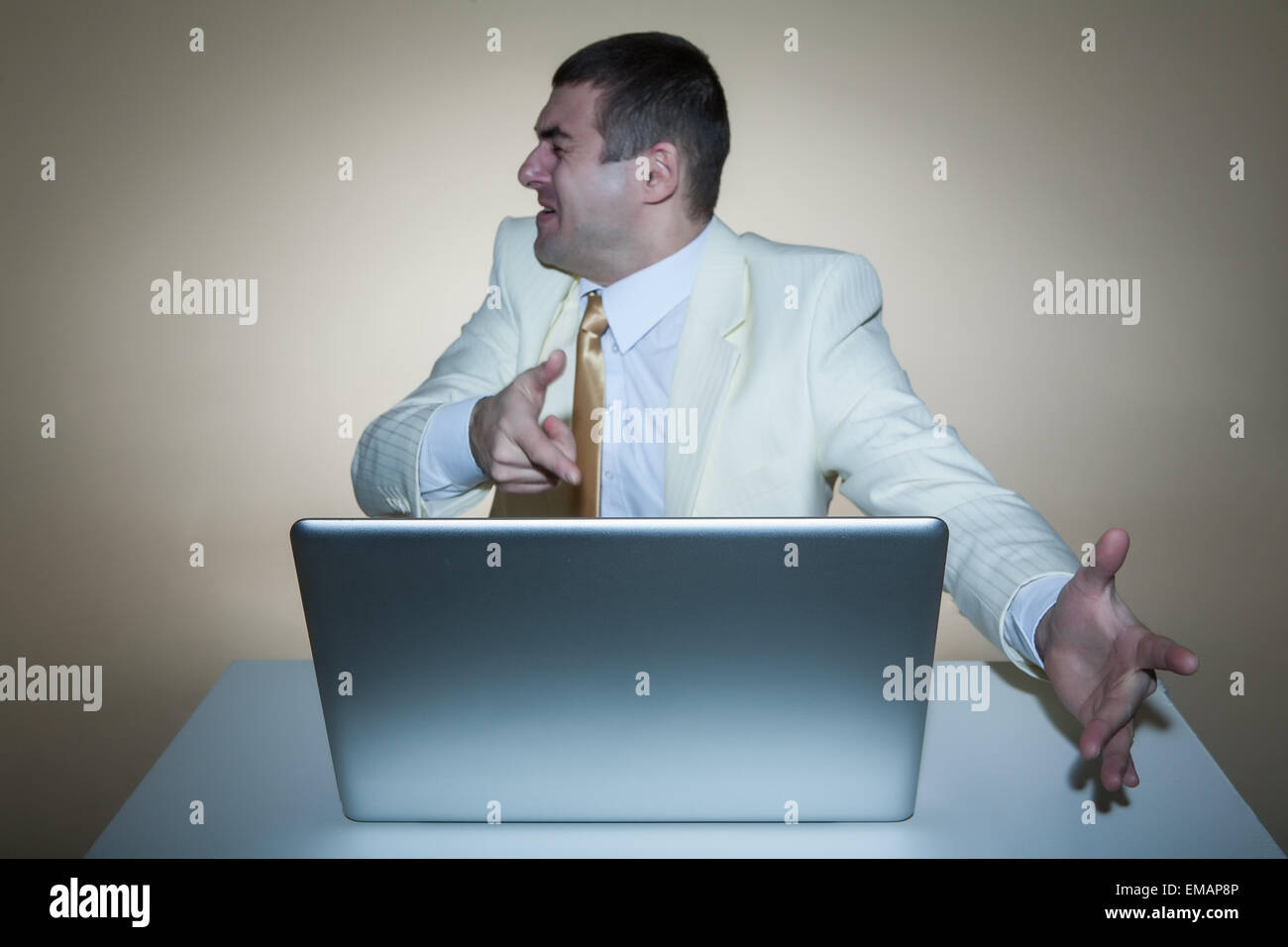 Ein Mann in einem weißen Anzug mit einem Laptop sitzt. Macht Handbewegungen. Lebendige Emotionen. Stockfoto