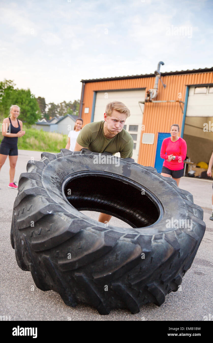 Starker Mann kippt schwere Reifen im Freien Training Stockfoto