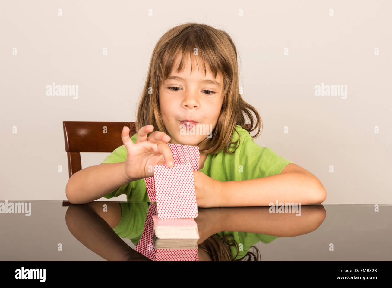 Porträt des kleinen Mädchens Spielkarten und ziehen Sie die Zunge Stockfoto