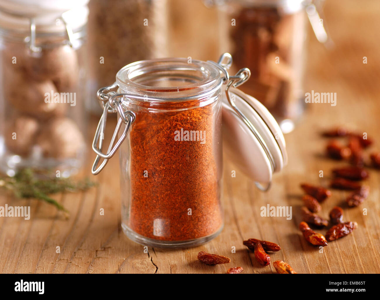 Chili-Pulver in das Glasgefäß auf Holztisch Stockfoto