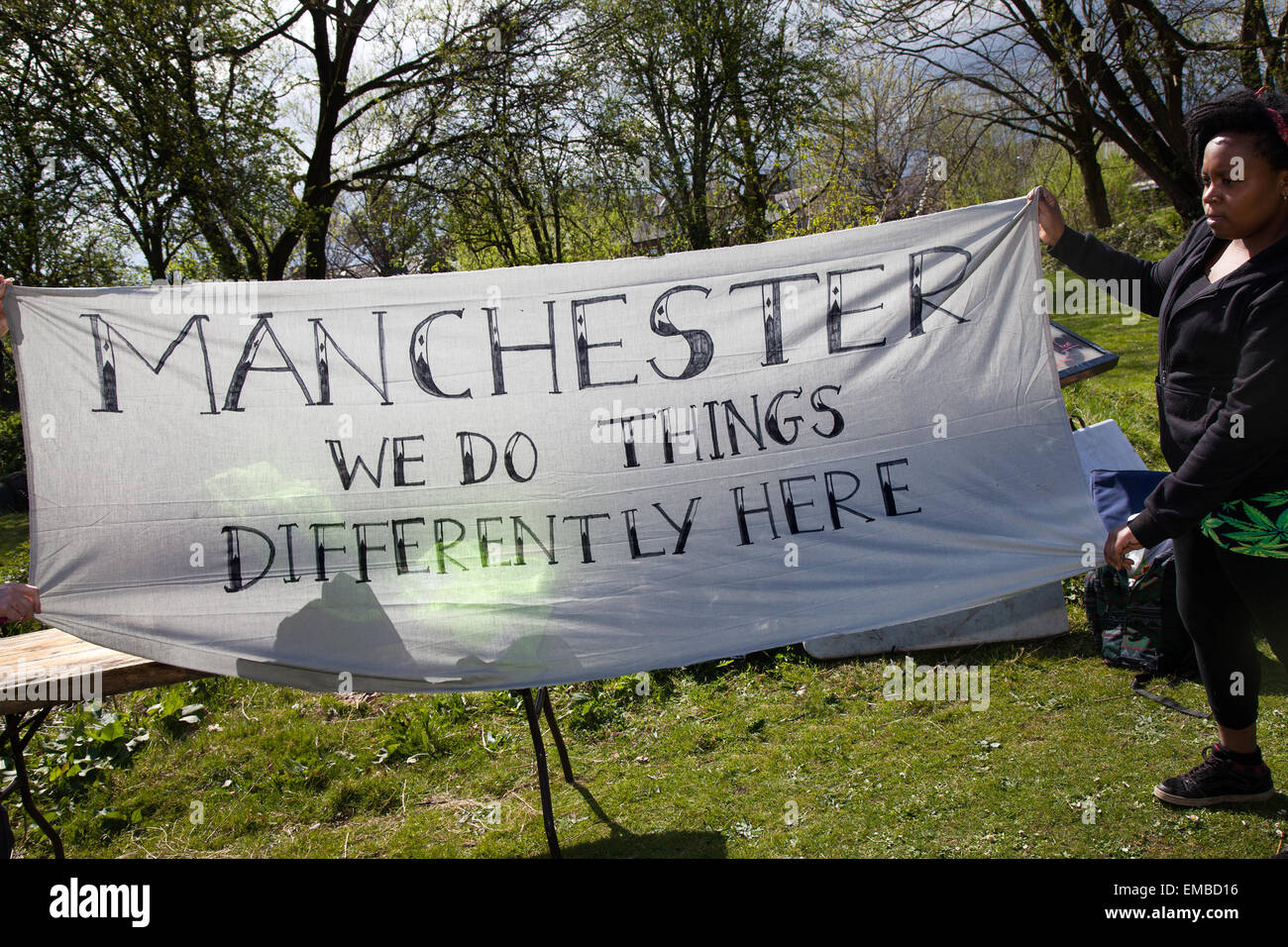 Manchester, UK, 19. April 2015. Cannabis Festival - goer auf Platt Felder Park holding Banner lesen "Wir tun Dinge anders hier' dieses '420' Ereignis wird als Mini-Festival für Menschen, Reefer-Puffing, Unkraut Raucher, Ganja-bezogenen Aktivitäten von Menschen, die sich für die Legalisierung von Cannabis Kultur Unterstützung geworben. Polizisten warnten sie einen skeptischen Blick auf jemand Drogen nimmt an der diesjährigen Puff-Puff-Pass Tag Veranstaltung nehmen würde. Greater Manchester Police und haben eine Reihe von verbalen Warnungen an die Leute so tun. Der Begriff "420" allgemein als Codewort für Kiffen bekannt geworden ist. Stockfoto