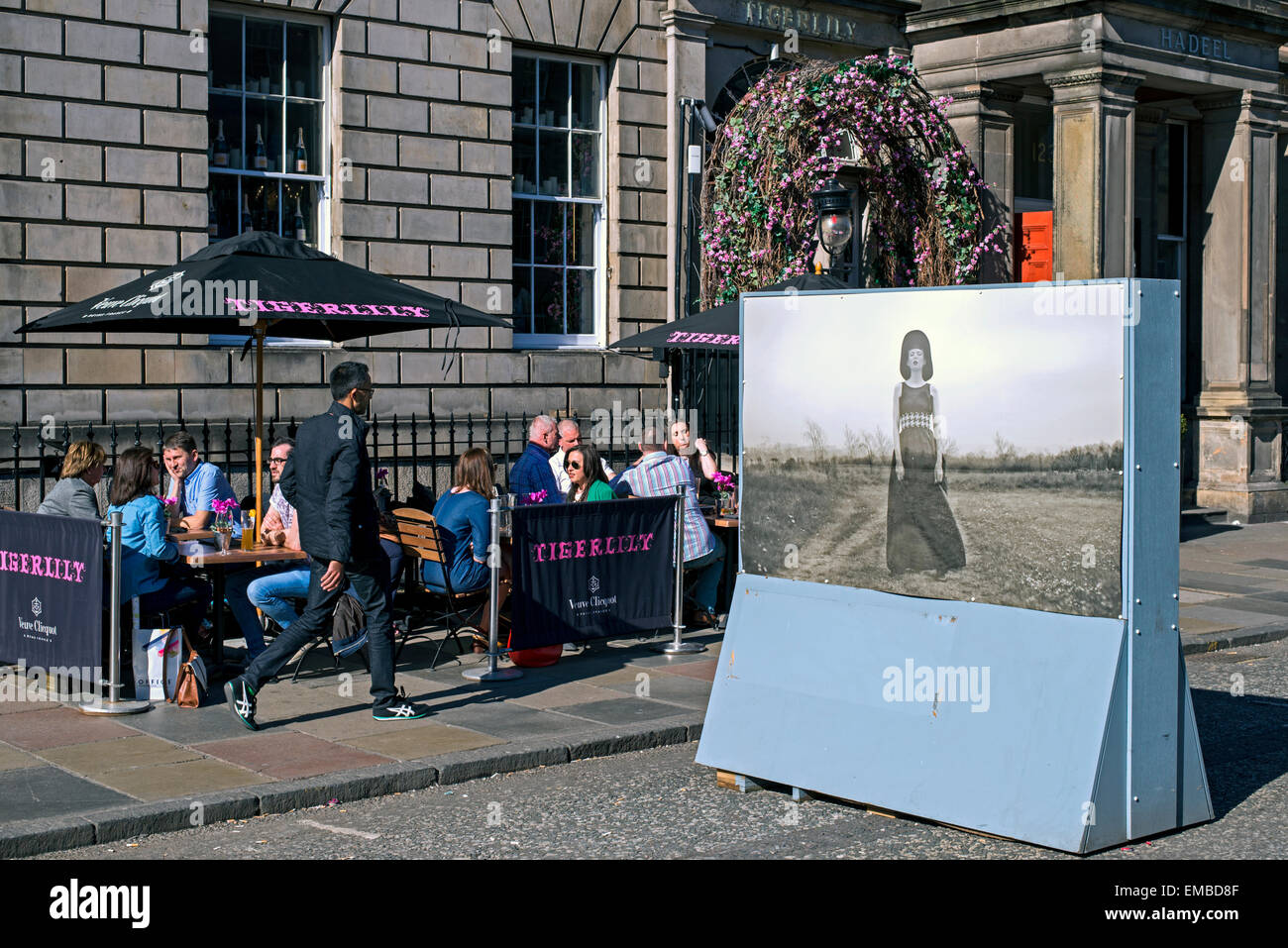 American Diner Essen außerhalb Tigerlily auf der George Street, während Teil einer outdoor-Mode-Fotografie-Ausstellung ein Fußgänger vorbeigeht. Stockfoto
