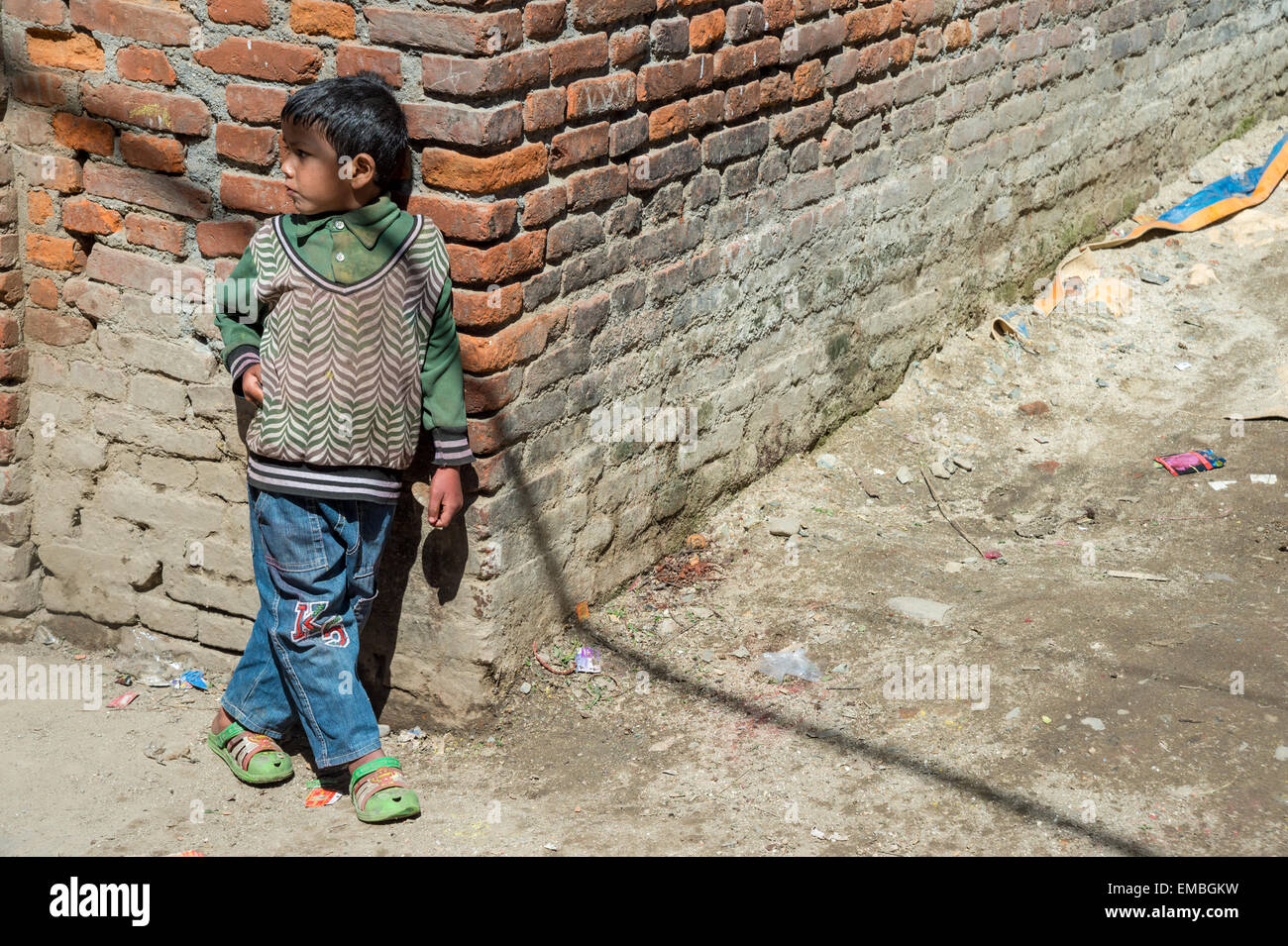 Ein kleiner Junge lehnt gegen eine Wand in Kathmandu Stockfoto