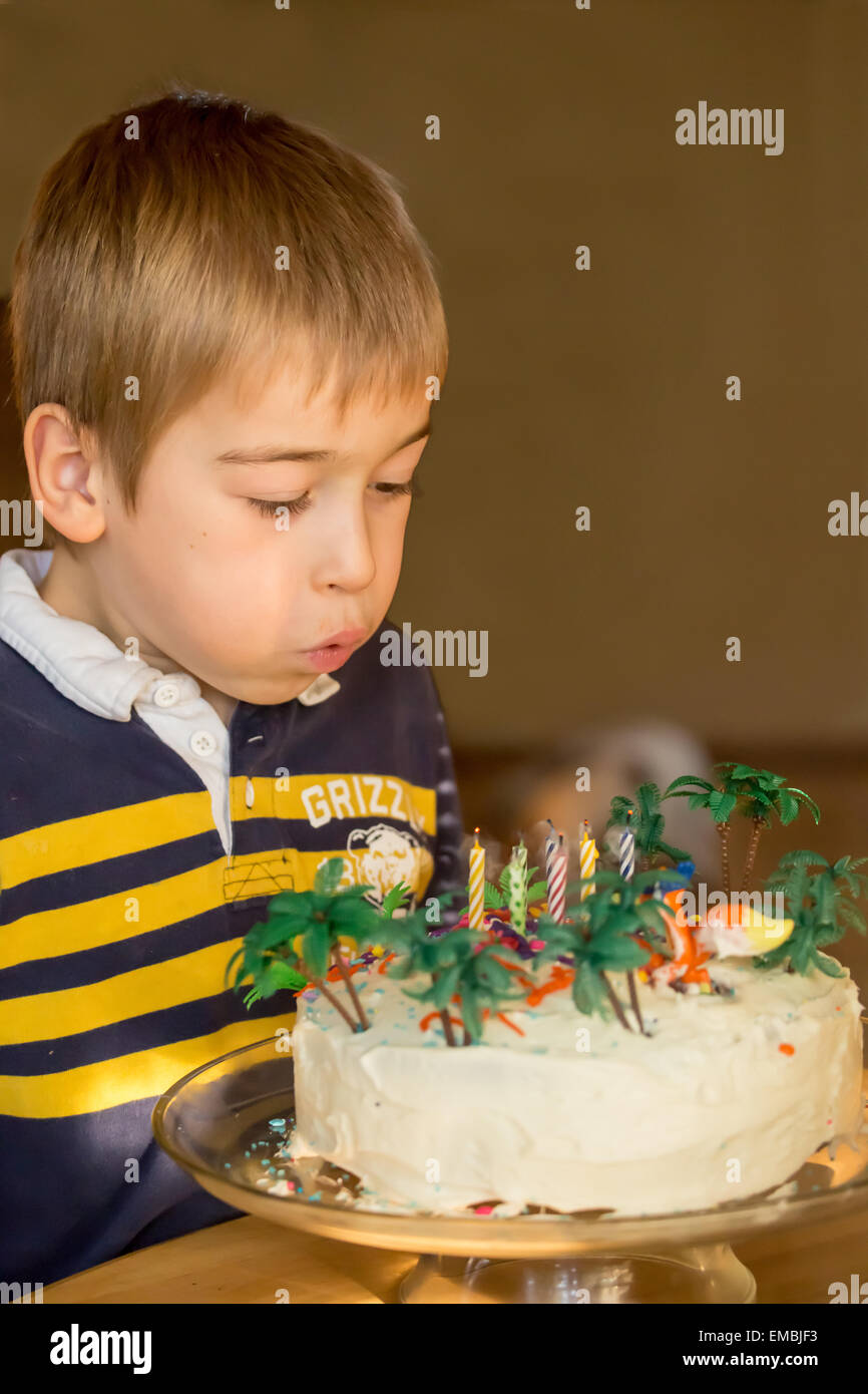 Sieben Jahre alter Junge Ausblasen der Kerzen auf seine Geburtstagstorte in Issaquah, Washington, USA Stockfoto