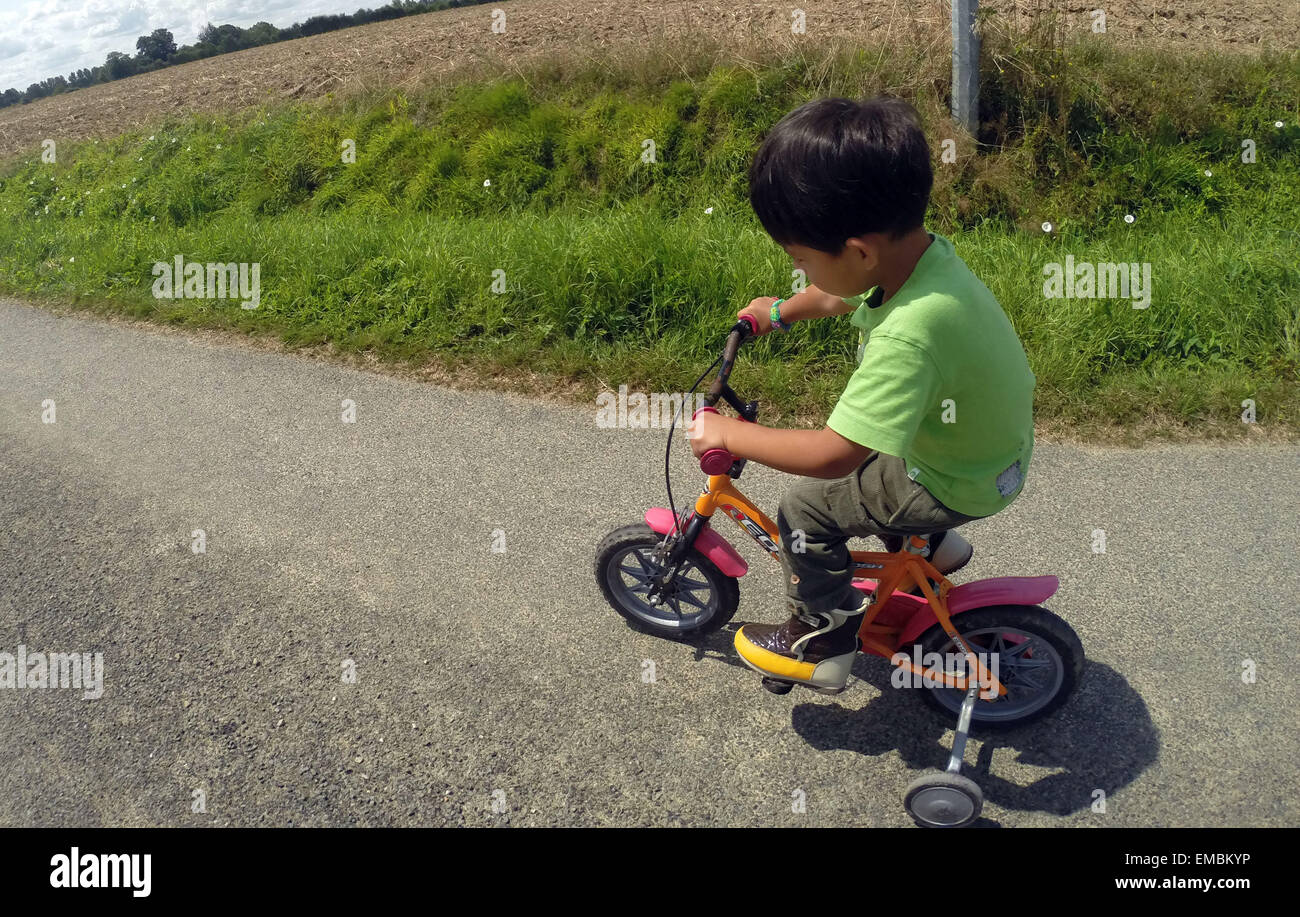 Es ist ein Foto von ein junges Kind oder Kind, das auf einer Straße in der Landschaft von Frankreich mit einem Dreirad Fahrrad ist. Er ist allein & 5 Jahre Stockfoto