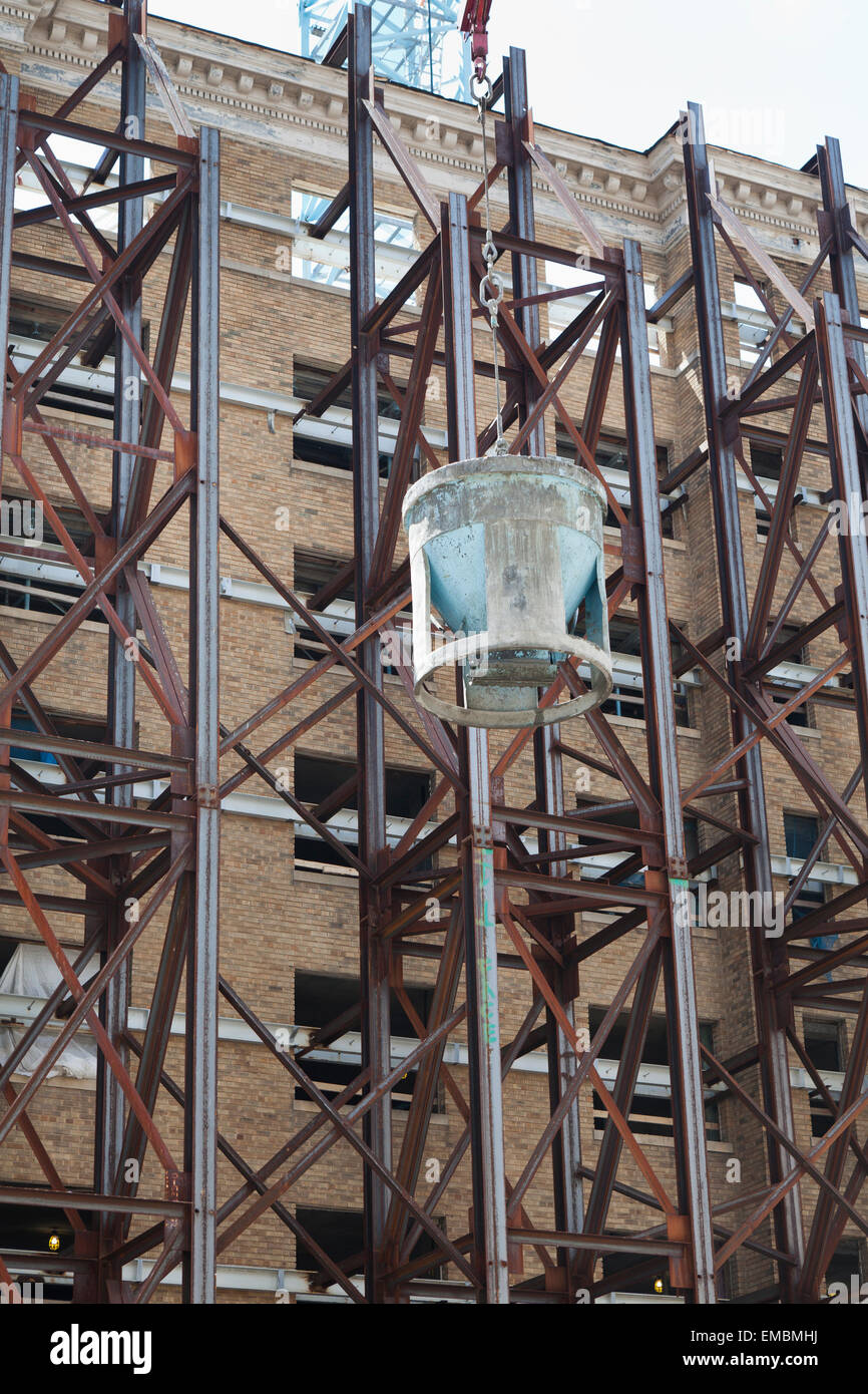 Betoneimer, der mit einem Kran an einer Baustelle zur Gebäudesanierung angehoben wurde - USA Stockfoto