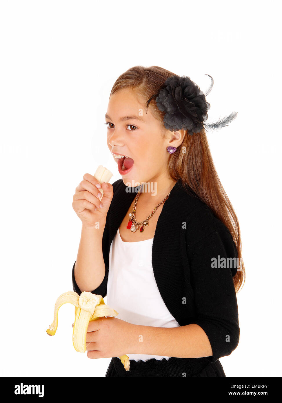 Ein acht Jahre altes Mädchen hielt eine Banane in der Hand zu essen, für weißen Hintergrund isoliert. Stockfoto
