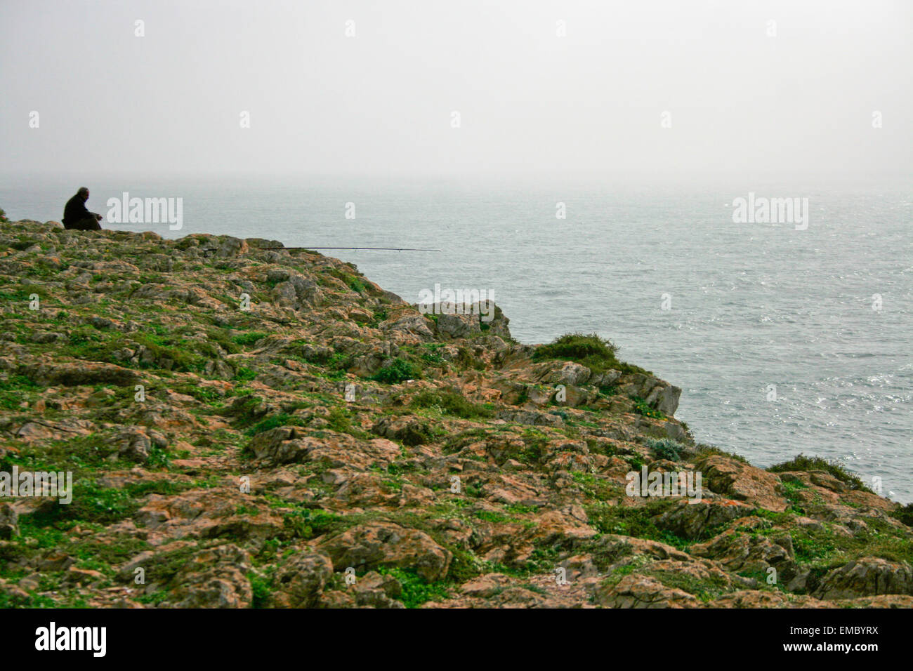 Ein Mann fischt auf Felsen am Cape Sagres Klippen, Portugal Stockfoto