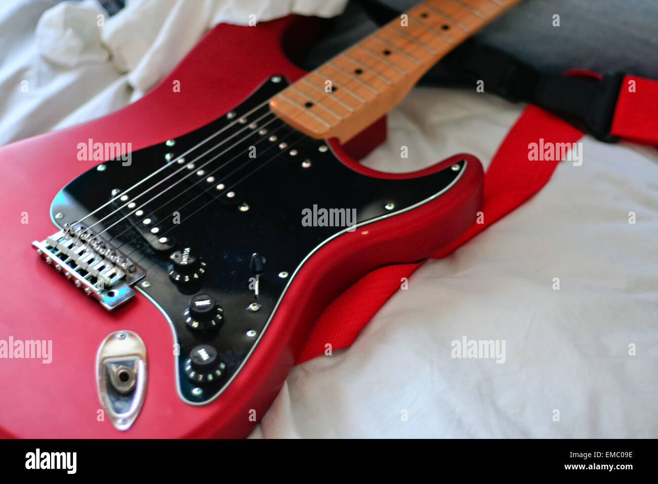 Unbekannter Mann reinigt seine e-Gitarrenhals mit einem weißen Tuch über dem Bett Stockfoto