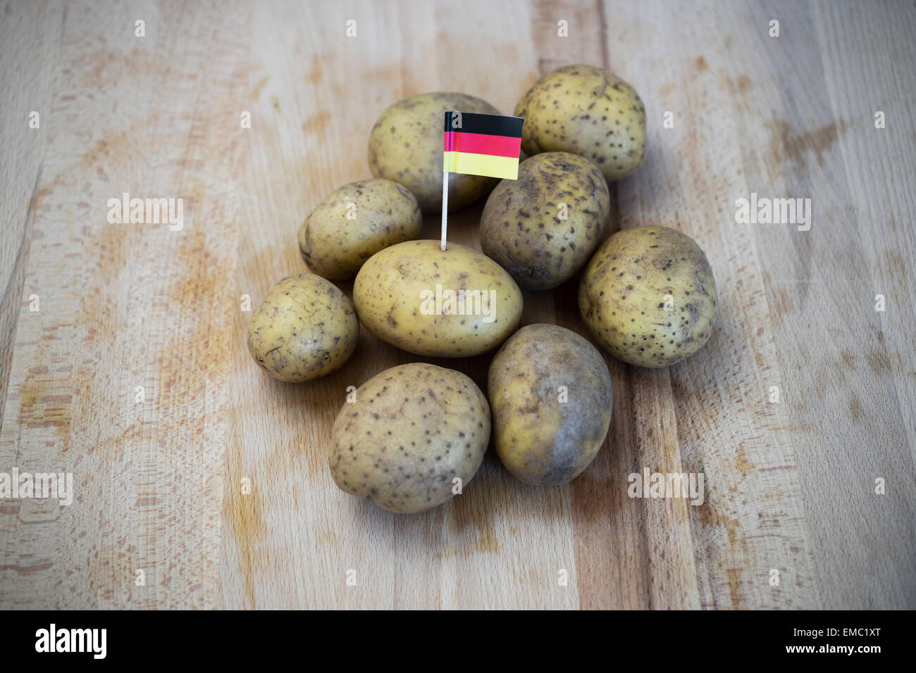 Zeile Kartoffeln und kleine deutsche Fähnchen auf Holz Stockfoto