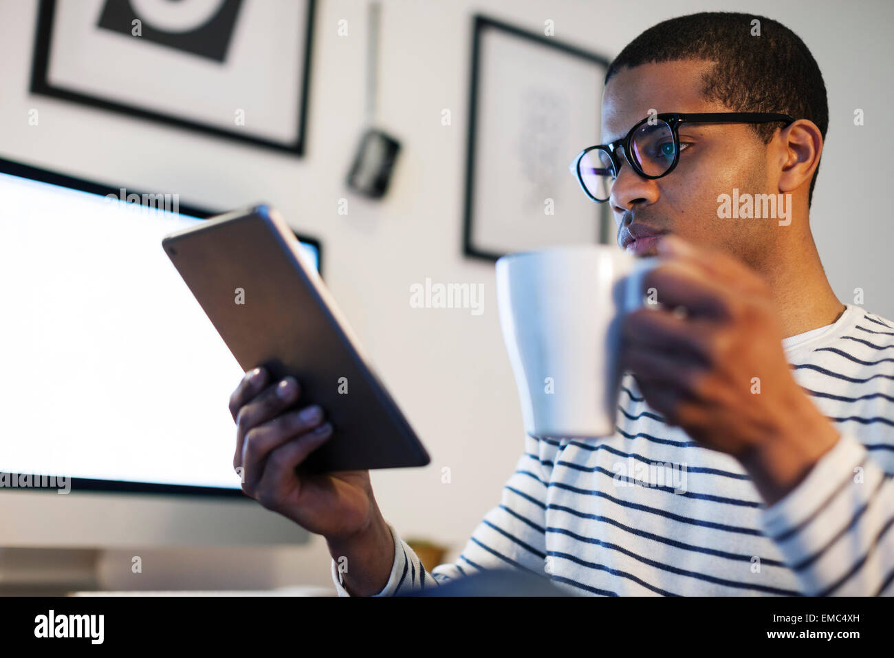 Kreative Jüngling mit Mini-Tablet mit Kaffeepause in seinem Büro zu Hause Stockfoto