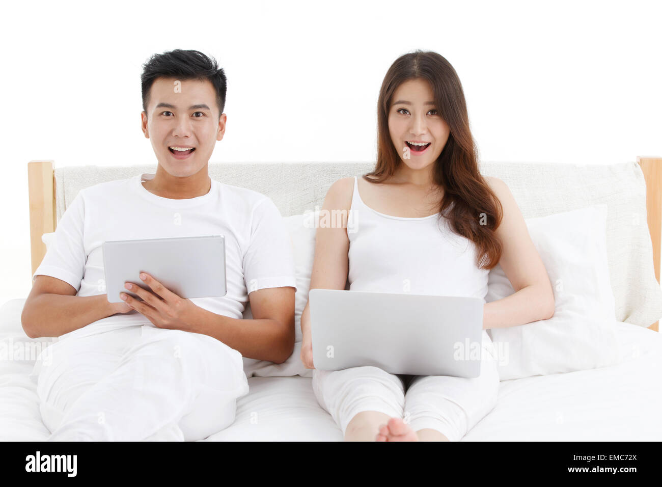 Junge Paare nutzen Computer im Bett Stockfoto
