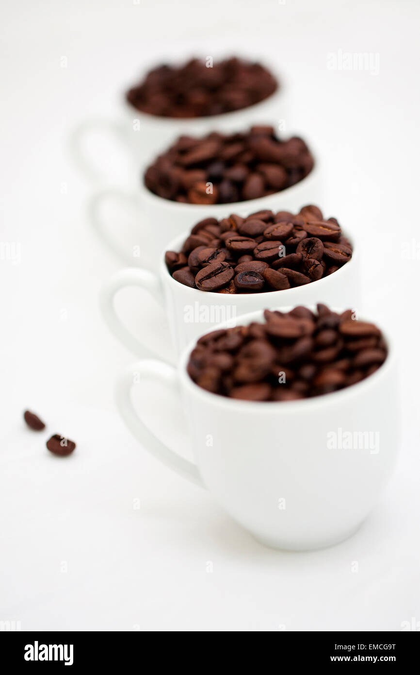 Vier weiße Tassen Kaffee Bohnen auf weißem Grund Stockfoto