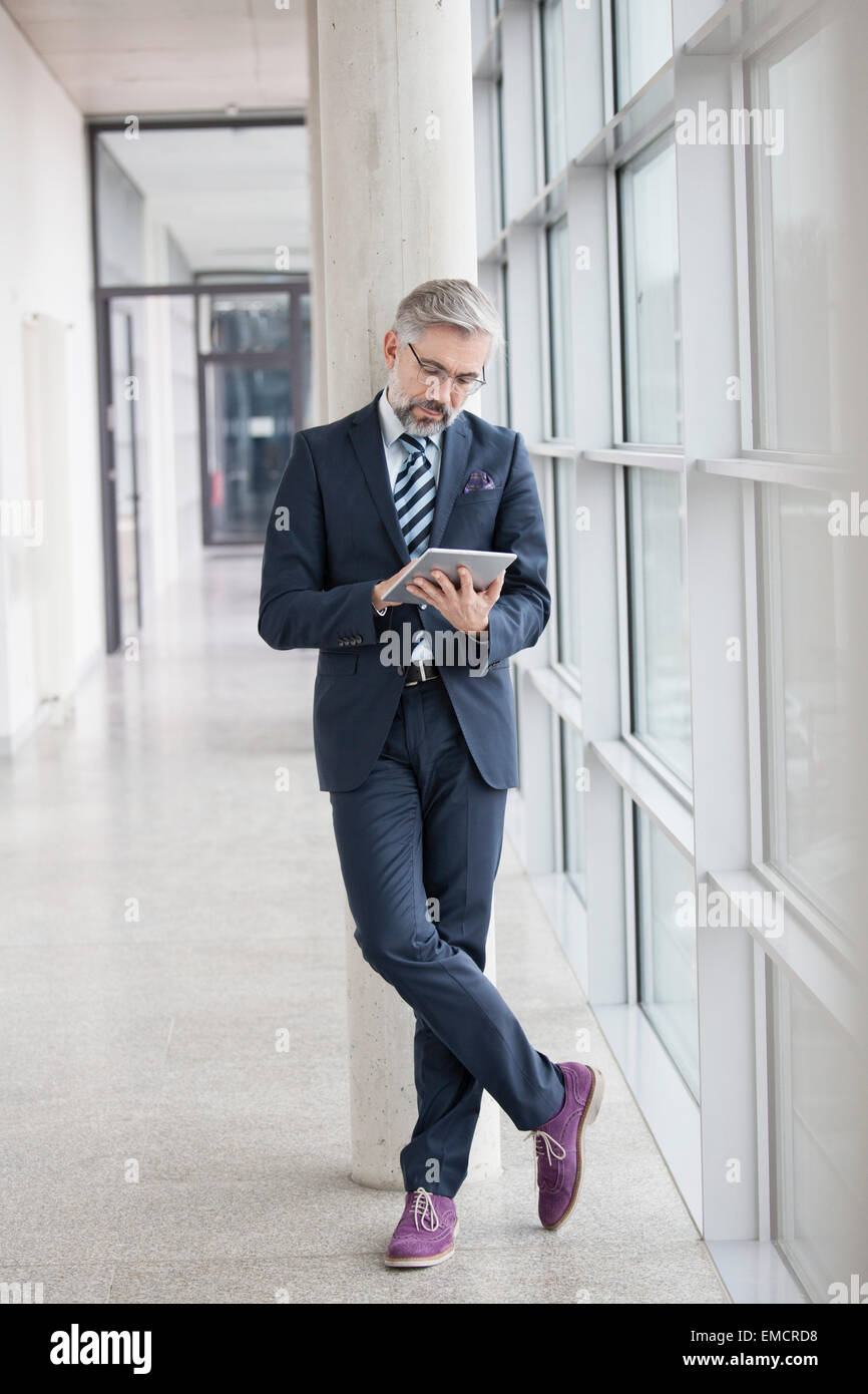 Geschäftsmann gelehnt Spalte mit digital-Tablette Stockfoto