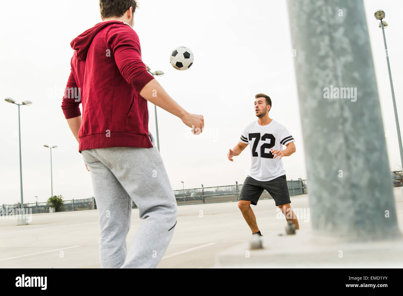 Zwei junge Männer spielen Fußball auf Parkdeck Stockfoto