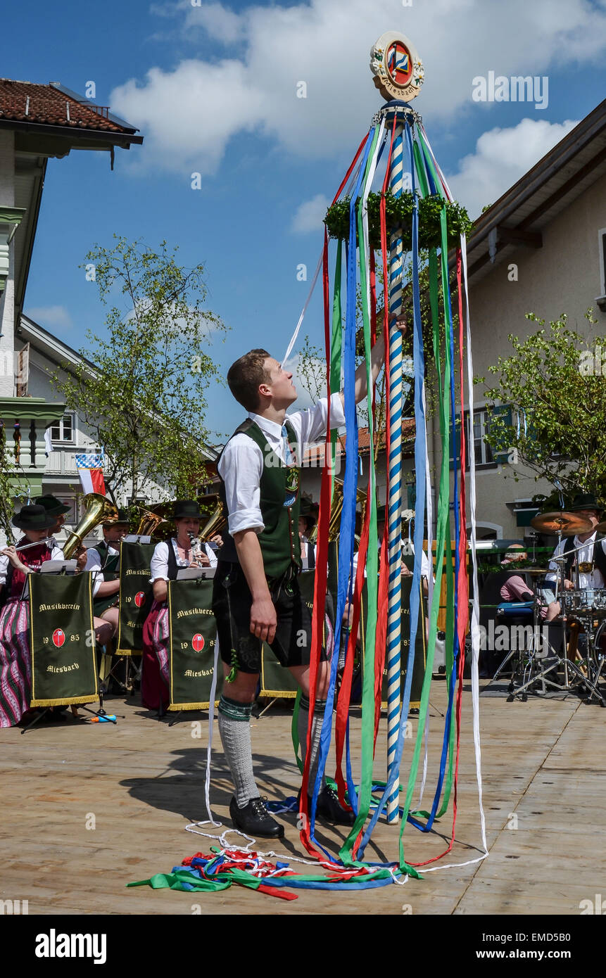 1. Maifeiertag-Maibaum Tradition Folklore-Gruppe traditionelle Kostüme "Dirndl" "Lederhose" Weben bunte Bändern um den Pol Stockfoto