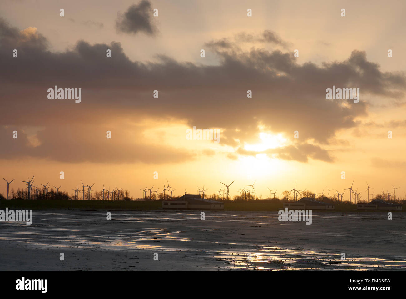 Deutschland, Bensersiel, Küstenlandschaft mit Windkraftanlagen bei Sonnenuntergang Stockfoto