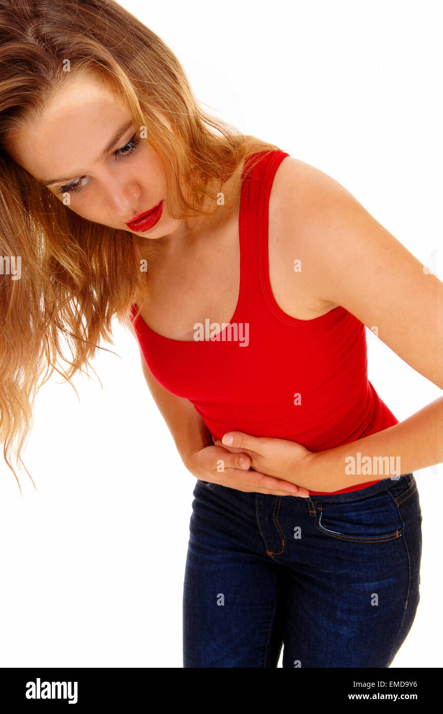 Eine junge, blonde Frau in einem roten T-shirt und Jeans stehen für weißen Hintergrund isoliert halten ihr Magen Schmerzen. Stockfoto