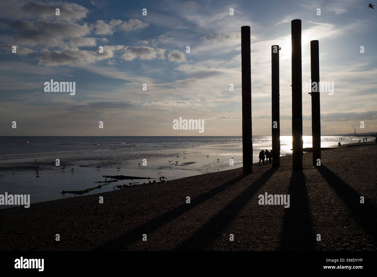 Menschen am Strand, alte Pier stützen, Sonnenuntergang, Ebbe, Strand von Brighton, UK Stockfoto