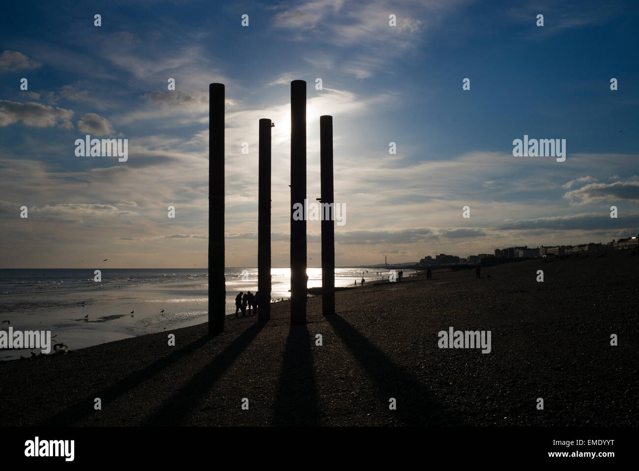 Menschen am Strand, alte Pier stützen, Sonnenuntergang, Ebbe, Strand von Brighton, UK Stockfoto