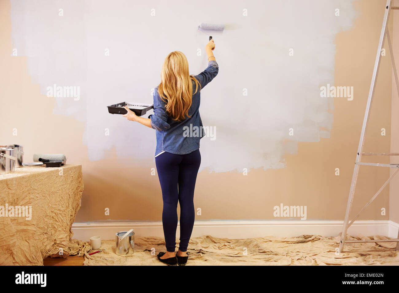 Frau Raum mit Farbroller auf Wand dekorieren Stockfoto