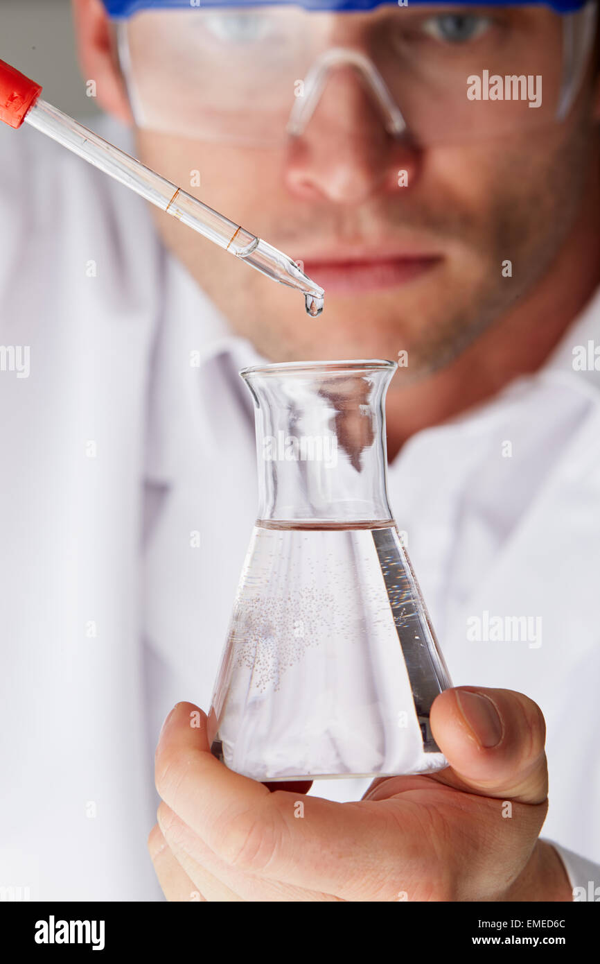 Wissenschaftler, die Kolben aus Pipette Flüssigkeit hinzufügen Stockfoto