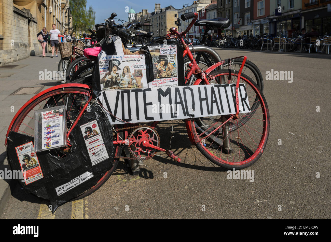 Ein Fahrrad abgestellt auf Broad Street, Oxford, Großbritannien am 20. April 2015 Förderung der Mad Hatter Kandidat für Oxford Osten in den britischen Parlamentswahlen 2015. Der verrückte Hutmacher richtiger Name ist Alasdair de Voil, ein lokaler Geschäftsmann gegen die etablierten M.P. Andrew Smith (Labour) in Oxford East Ward. Stockfoto