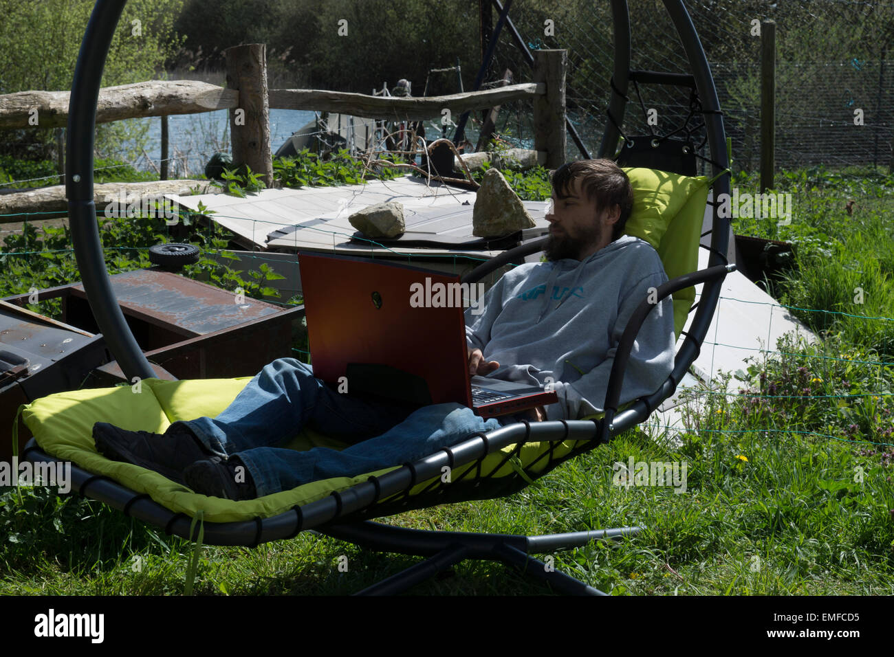 Junger Mann, ist entspannend, draußen im Garten. Überarbeitung zu tun und Gaming, ein Videospiel draußen spielen. Stockfoto