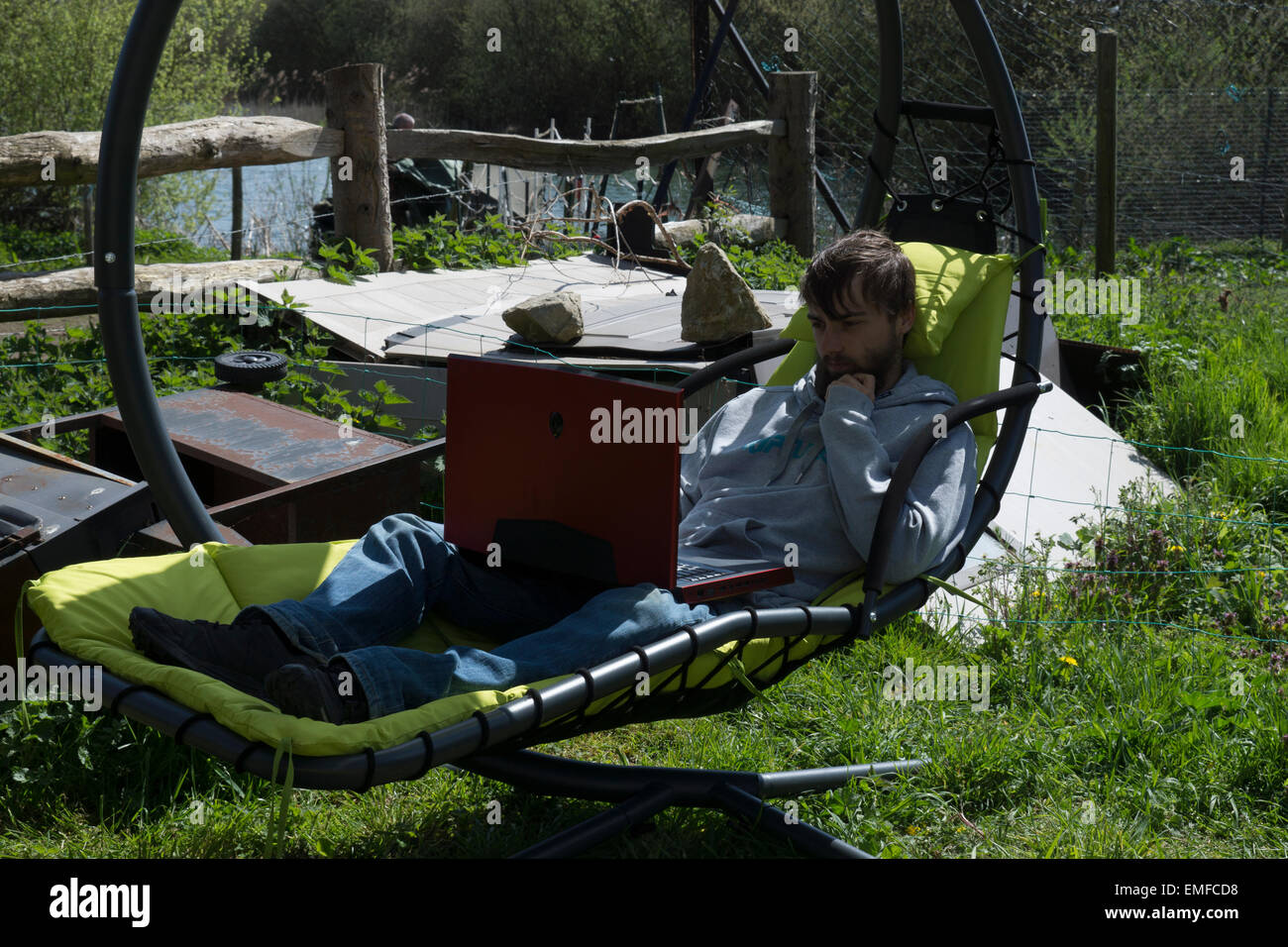 Junger Mann, ist entspannend, draußen im Garten. Überarbeitung zu tun und Gaming, ein Videospiel draußen spielen. Stockfoto