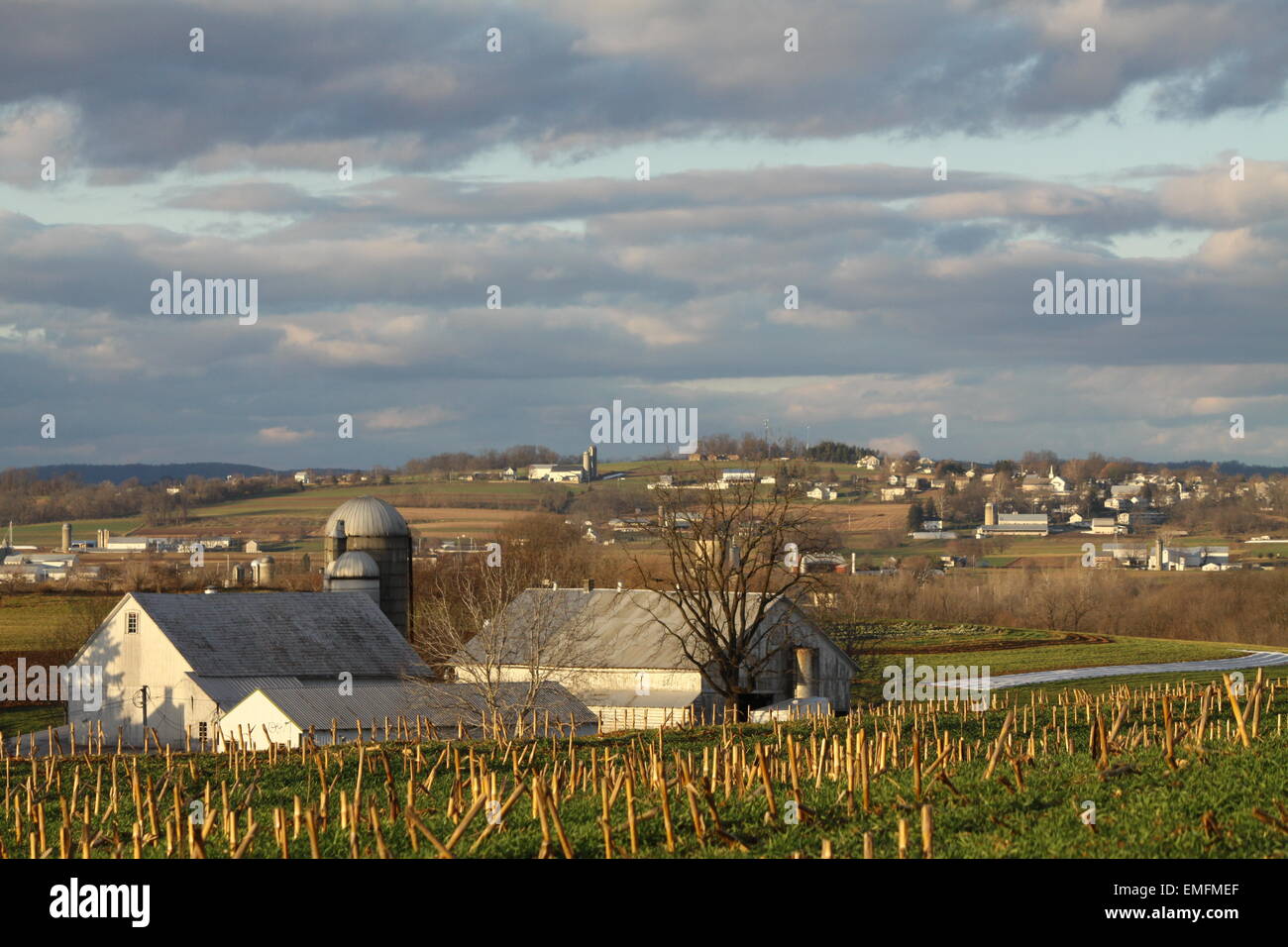 An einem kalten land Wintertag, auf einer hügeligen Anhöhe blickte auf eine ordentlich aussehende Bauernschaft, Gebäude und Ernte. Stockfoto
