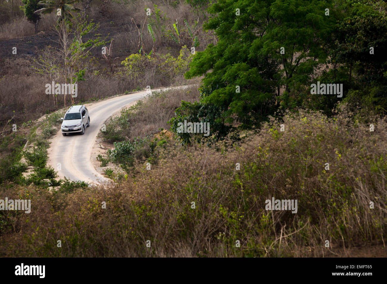 Ein Auto fährt auf einer Landstraße in Sumba, einer abgelegenen Insel in der indonesischen Provinz Ost-Nusa Tenggara. Stockfoto
